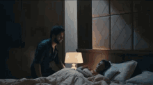 a man is standing next to a woman in a bed .