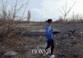 a boy in a blue shirt is standing in a rocky area with the word poxyui written on the bottom