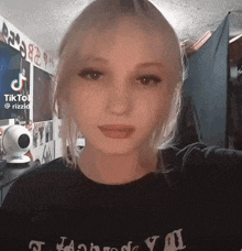 a girl with blonde hair is wearing a black shirt and taking a selfie .