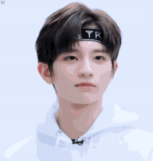 a young boy wearing a headband and a white hoodie is making a funny face .
