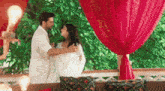 a man and a woman are dancing in front of a red curtain in a room .