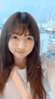 a girl with long hair and bangs is smiling and taking a selfie