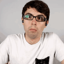 a man wearing glasses and a white shirt has a black cat pocket