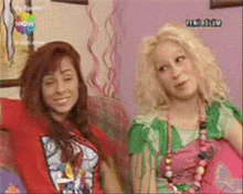 two women sitting next to each other on a couch with a tv screen that says show