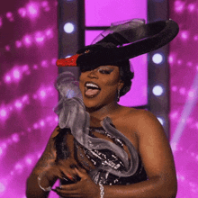 a woman wearing a black hat with a red bow on it is laughing