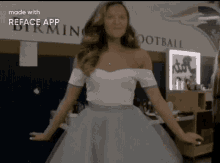 a woman in a white dress is standing in front of a wall that says birming football