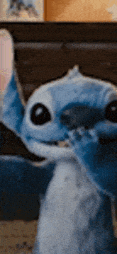 a close up of a stuffed animal , stitch , sitting on a bed .