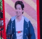 a man wearing a blue jacket and a white shirt is standing in front of a screen .