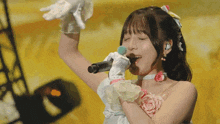 a woman in a white dress singing into a microphone with her eyes closed