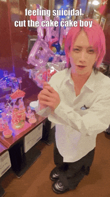 a man with pink hair is kneeling in front of a table with cupcakes and balloons and a caption that says feeling suicidal