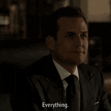 a man in a suit and tie says everything in a dark room