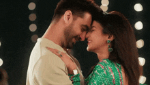 a man and a woman are touching their foreheads and smiling .