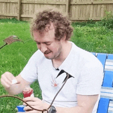 a man with curly hair is sitting on a blue and white chair in the grass