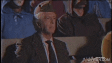 a man in a suit and tie is playing a mandolin in front of people