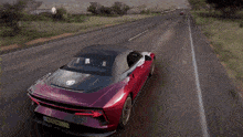 a red sports car with a black top is driving down the road