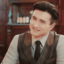 a man in a suit and tie is smiling in front of bottles