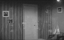 a black and white photo of a room with striped wallpaper and pictures on the walls .