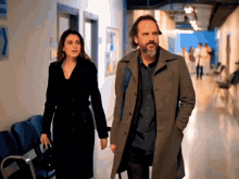 a man and a woman are walking down a hallway in front of a sign that says 2
