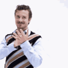 a man wearing a striped vest and tie is clapping his hands