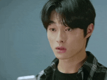 a young man is looking at his phone with a surprised look on his face .