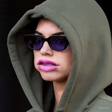 a woman wearing purple sunglasses and a green hoodie with the word meta at the bottom right