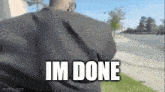 a man in a black shirt is walking down a sidewalk with the words `` im done '' written on his back .