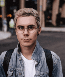 a man wearing glasses and a denim jacket