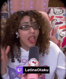 a woman wearing glasses and a hello kitty shirt is holding a microphone and says latinaotaku at the bottom