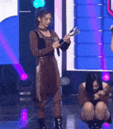a woman is kneeling down on a stage holding a microphone