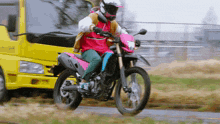 a person riding a motorcycle in front of a yellow truck that says ' a ' on it