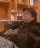 a woman wearing a hat is sitting on a couch with her eyes closed .