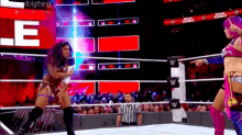 two women are wrestling in a wrestling ring while a referee points at them .