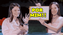 two women holding up a sign that says por mimi