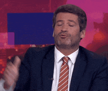 a man in a suit and tie is making a gesture with his hands