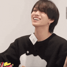 a young man wearing a black sweater has a name tag around his neck that says ' yuta ' on it