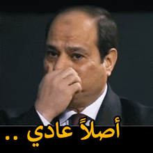 a man in a suit and tie is covering his nose with his hand with arabic writing below him
