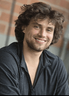a man with curly hair and a beard is smiling