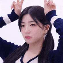 a girl in a blue and white sweater makes a peace sign with her hands