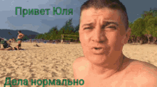 a shirtless man stands on a sandy beach with russian writing on the bottom right