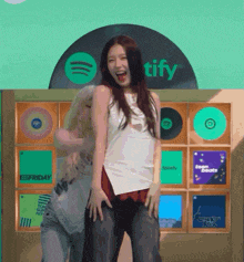 two women dancing in front of a spotify sign