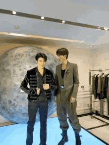 two men are standing next to each other in a room in front of a giant ball .