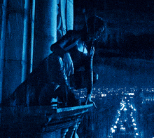 a woman sitting on a balcony looking out over a city at night
