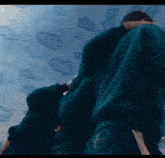 a man in a green sweatshirt is standing in front of a ceiling with clouds painted on it