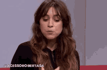 a woman with long hair is sitting on a red couch and making a face .