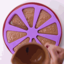 a person is pouring chocolate into a purple silicone tray