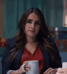 a woman sitting at a table holding a mug