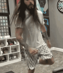 a man with long hair and a beard is dancing in a room with a sign that says mc