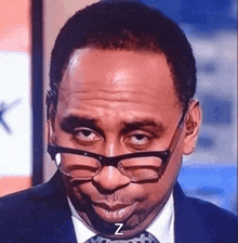 a man wearing glasses and a suit and tie is making a funny face with the letter z next to him .