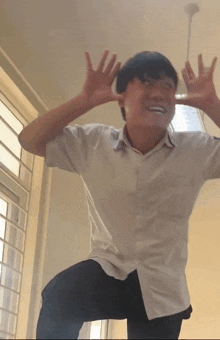 a young man in a white shirt and black pants is making a funny face
