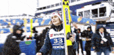 a woman holding a pair of skis with the number 33 on the front
